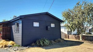 A small, dark-colored shed with a sloped roof, a window, and a door.
