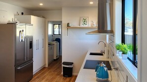 A modern kitchen with a stainless steel refrigerator, a kettle, and a window with a view.
