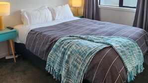 A hotel room with a bed, bedside lamps, a window, and a ceiling fan.