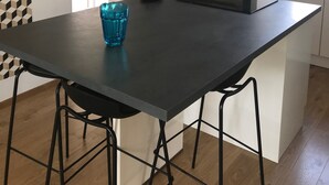Una cocina moderna con una isla central, luces colgantes, horno empotrado y un refrigerador con una etiqueta BISTROT.