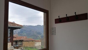 A room with a large window offering a view of a mountainous landscape and traditional buildings. - Casa el Enebral (Colio)