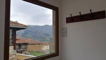 Une pièce dotée d’une grande fenêtre donnant sur un paysage montagneux et des bâtiments traditionnels.