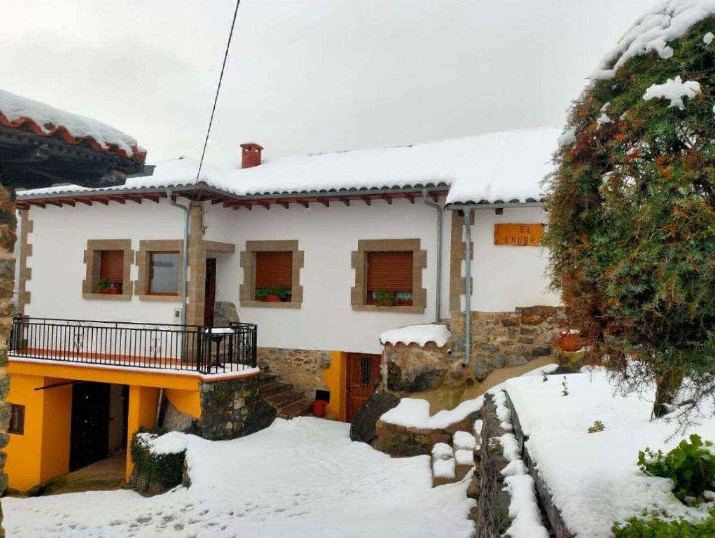 A traditional stone house with a balcony, surrounded by snow.