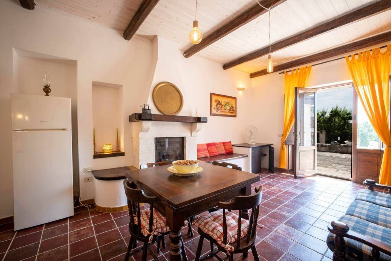 Un'accogliente cucina con tavolo e sedie, frigorifero, camino e vista sull'esterno.