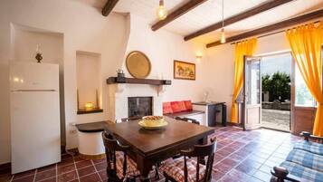 Un'accogliente cucina con tavolo e sedie, frigorifero, camino e vista sull'esterno.