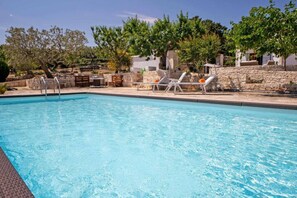A swimming pool with lounge chairs and a stone wall. - WePuglia - Trullo Sentimento (Martina Franca)