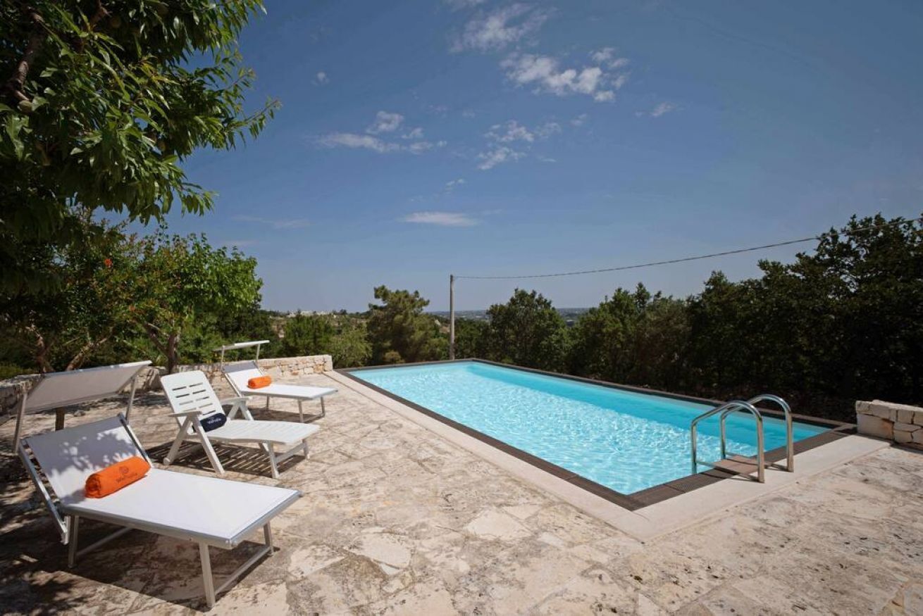 Una piscina con lettini da sole e un solarium in pietra.
