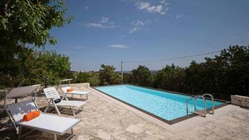Una piscina con lettini da sole e un solarium in pietra.