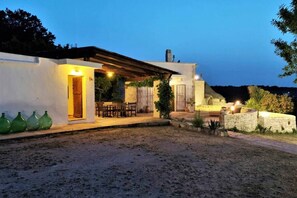 A modern house with a covered patio, outdoor seating, and a stone wall. - WePuglia - Trullo Sentimento (Martina Franca)