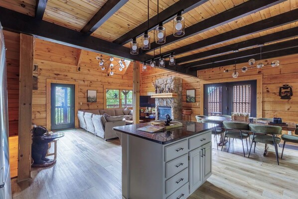 A log cabin interior with a central island, dining area, and a fireplace.