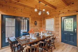 Un interior de madera con una mesa de comedor preparada para cuatro personas, rodeada de sillas de madera.