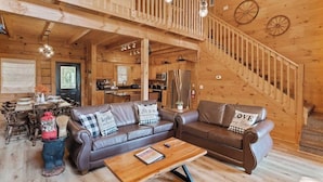 A wooden interior with a staircase, two leather sofas, a wooden coffee table, and a dining area. - 5 bdrm MT view, 10 mins DT,Hot Tub (Gatlinburg)