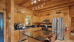A wooden cabin interior with a kitchen featuring a central island, stainless steel appliances, and wooden cabinets. - 5 bdrm MT view, 10 mins DT,Hot Tub (Gatlinburg)