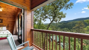 A wooden cabin with a balcony, a bed, and a view of a forested landscape. - 5 bdrm MT view, 10 mins DT,Hot Tub (Gatlinburg)