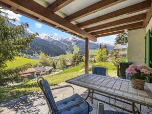 Une terrasse avec une table et des chaises donnant sur un paysage montagneux.