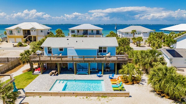 Una propiedad frente a la playa con piscina, varias habitaciones para huéspedes y vista al océano.