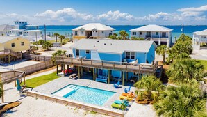 Une propriété située en bord de mer, dotée d’une piscine, de plusieurs bâtiments et d’une terrasse en bois.