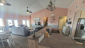 Une cuisine spacieuse avec un îlot central, un coin repas avec une table et des chaises, et un salon avec des canapés.