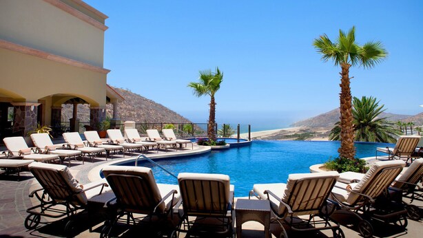 Un espace aménagé au bord de la piscine, avec des chaises longues et une vue sur l’océan.