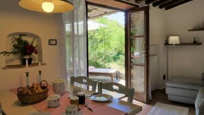 Un coin repas accueillant, avec une table dressée pour deux personnes, un panier de pain et un vase rempli de fleurs.