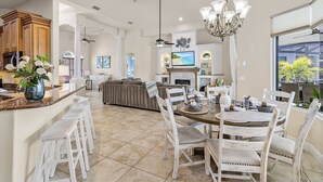 Uma cozinha espaçosa com área de jantar, uma ilha grande com banquetas e vista para o exterior.