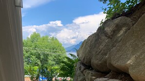 A stone retaining wall with a grassy area and a pathway leading to a view of trees and mountains. - Vista Unica Sulle Isole (Baveno)