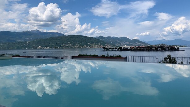 A clear view of a swimming pool with a mountain backdrop and a distant shoreline. - Vista Unica Sulle Isole (Baveno)
