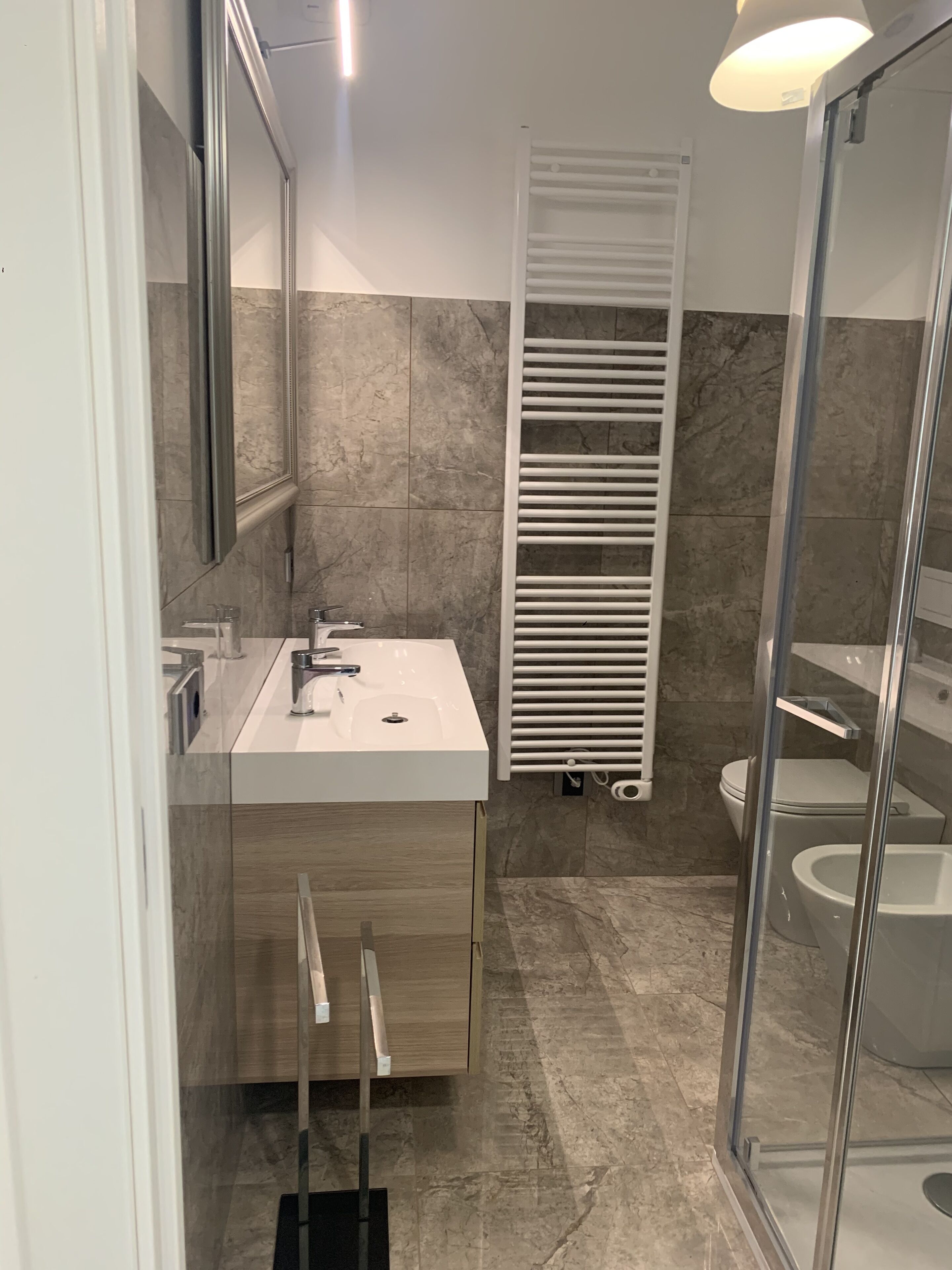 A modern bathroom with a white sink, a glass shower enclosure, and a towel rack.