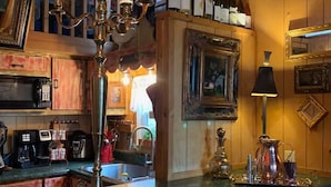 Een bar met een houten toonbank, verschillende wijnflessen, een kandelaar en ingelijste foto's aan de muur.