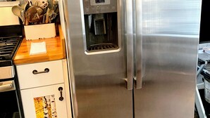 A stainless steel refrigerator with a water dispenser, a wooden countertop, and a kitchen sink.