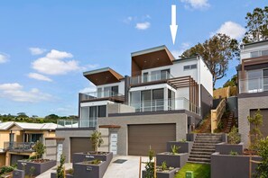 Un moderno complejo residencial con varias casas de dos pisos, una escalera central y un jardín bien cuidado.