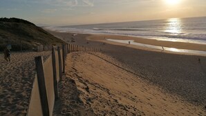 Una playa con una cerca de madera, un camino de arena y el océano.