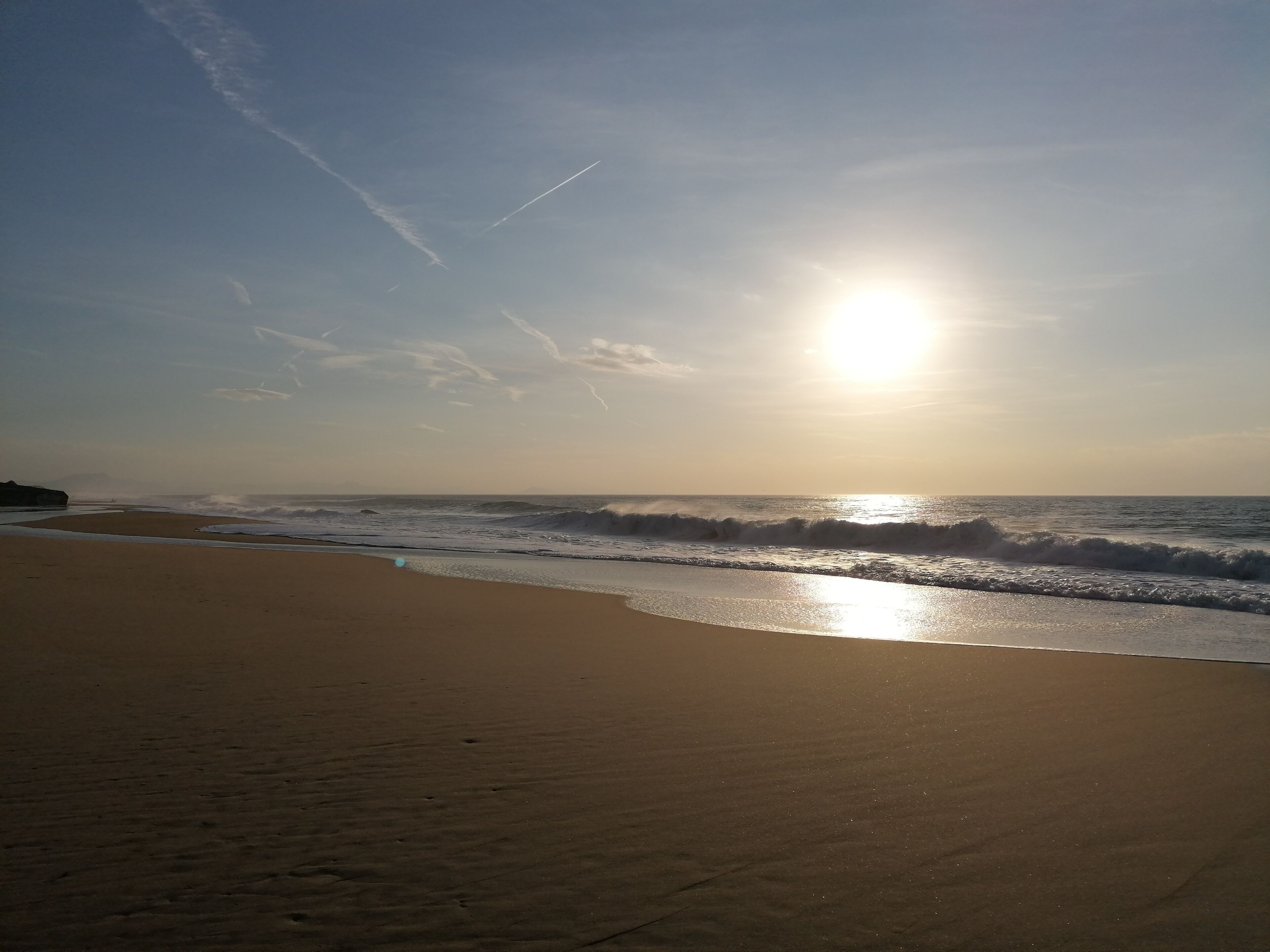 A beach with waves and a clear sky.