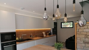 Una cocina moderna con encimera de madera, un microondas Bosch, un lavamanos y lámparas colgantes.