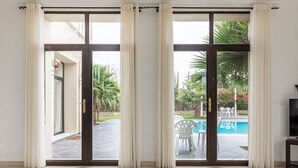 Amplia habitación con un gran ventanal corredero que da a un área exterior con piscina y palmeras.