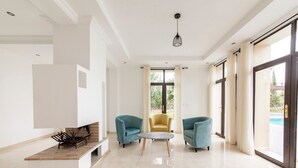 Amplia sala de estar con diseño moderno, que incluye una mesa de centro, dos sillones y un sofá.