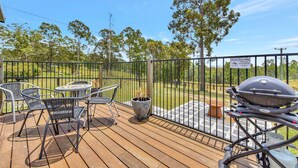A wooden deck with outdoor furniture, a grill, and a sign requesting cleanliness. - Wallaby Gully Farm Cottage Peace, Quiet, Serenity (Ellalong)