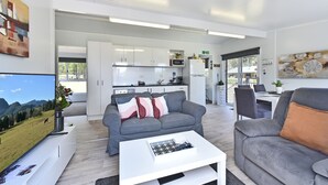 A modern living room with a grey sofa, a white coffee table, and a dining area with a table and chairs. - Wallaby Gully Farm Cottage Peace, Quiet, Serenity (Ellalong)