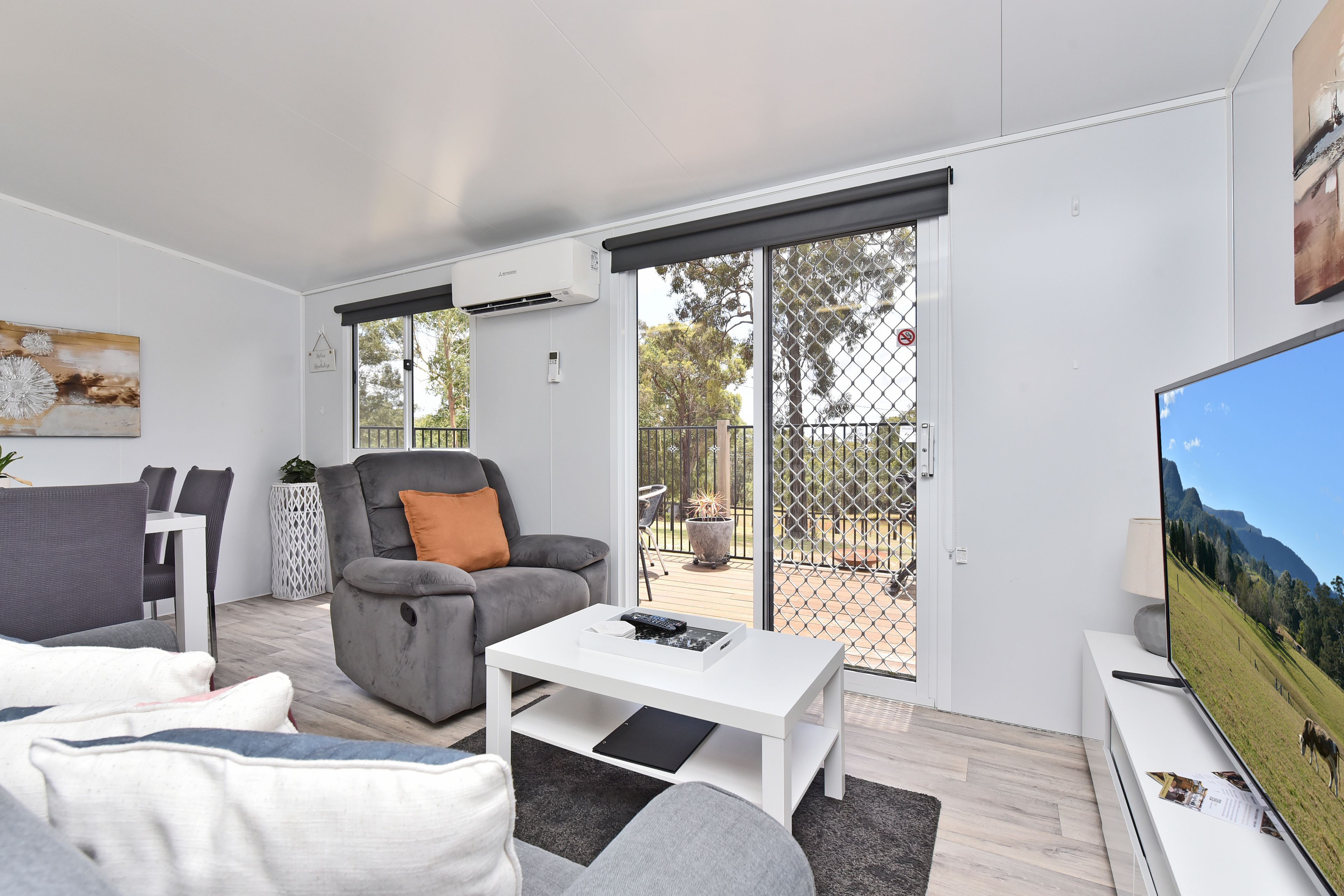 A modern living room with a grey sofa, a white coffee table, and a television.