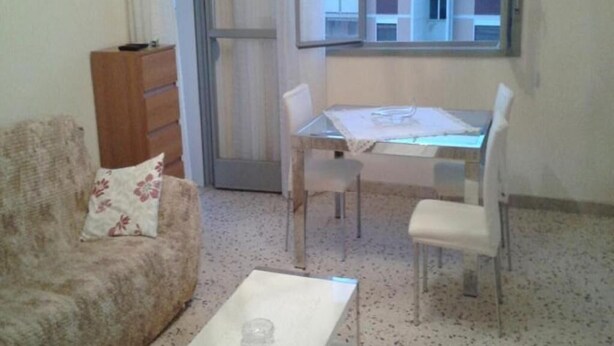 En hyggelig opholdsstue med sofa, sofabord, spisebord med stole og en skydedør til en udendørs balkon.