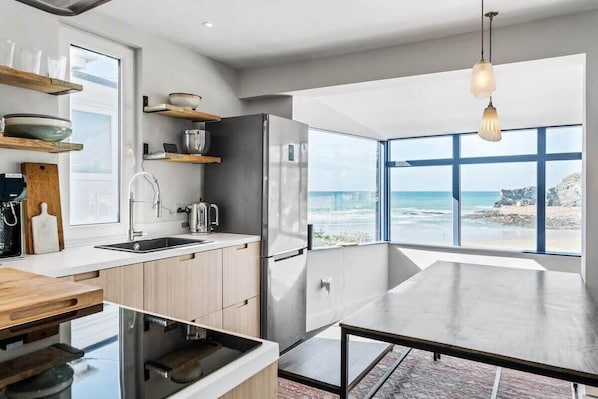 A modern kitchen with a large island, stainless steel appliances, and a view of the ocean. - Beach House with Stunning Sea Views (Portreath)