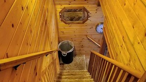 Interior de madera con una escalera, una lámpara y un reloj en la pared.