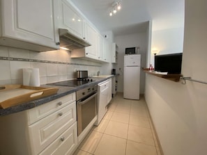 A compact kitchen with white cabinets, a built-in oven, a microwave, and a small countertop.