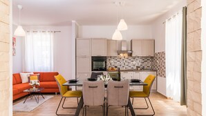 A modern kitchen with a dining area, featuring a dining table with chairs, a sofa, and a kitchen island. - Villa grotta istriana mit neu pool near center and Arena in Pula (Pula)