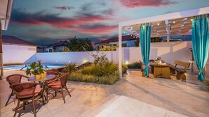 An outdoor patio with a pool, wicker chairs, a table, and a pergola with curtains. - Villa grotta istriana mit neu pool near center and Arena in Pula (Pula)