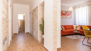 A modern living room with a wooden floor, a red sofa, a yellow chair, and a painting on the wall. - Villa grotta istriana mit neu pool near center and Arena in Pula (Pula)