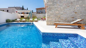 A swimming pool with tiled steps, lounge chairs, and a stone wall. - Villa grotta istriana mit neu pool near center and Arena in Pula (Pula)