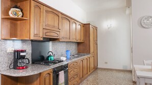 A kitchen with wooden cabinets, a stove, a coffee maker, and a kettle. - Small villa near the historic center with free parking (Assisi)