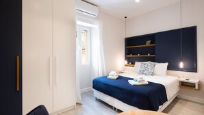 A modern hotel room with a bed, bedside tables, a wardrobe, and a window with curtains. - Corfu Town Twin Studios by CorfuEscapes (Corfu)