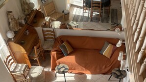 A cozy living area with a sofa, chairs, a dining table, and a staircase. - BALCONY SUR LA MARINE - VUE IMPRENABLE - STUNNING VIEW - BONIFACIO harbor (Bonifacio)